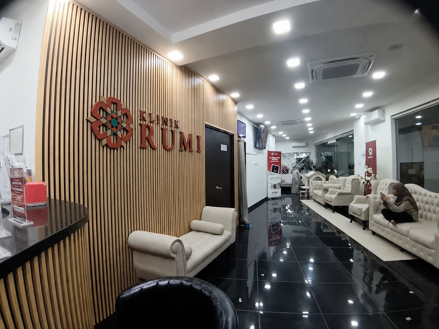 A Klinik Rumi reception, timber battens and a lit brand mark.
